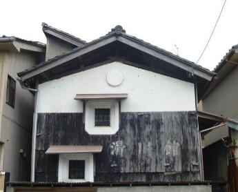 上半分が白、下半分が黒色の外壁、黒色の外壁部分に白字で「滑川館」と薄っすらと書かれているのがわかる滑川館道具蔵の写真