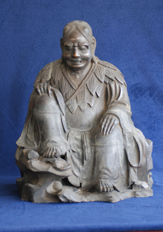 両手を膝の上に、右足を台の上にのせ座っており、目を見開き、歯を食いしばっているような表情をした神農坐像の写真