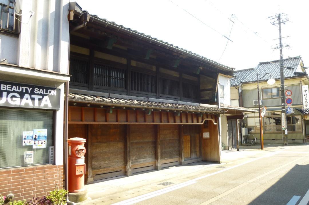木造2階建てで、2階窓に縦格子が見られる菅田家住宅主屋の外観写真