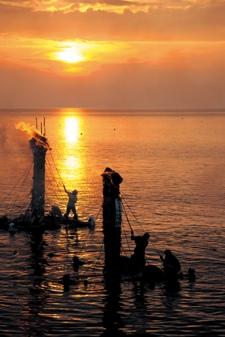 夕焼けの中に浮かび上がる2つのネブタ流しの写真