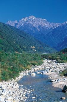 雪化粧の立山連峰を奥に望む早月川の写真