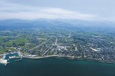 海側の上空から見た立山連峰と富山湾に囲まれた滑川市の写真