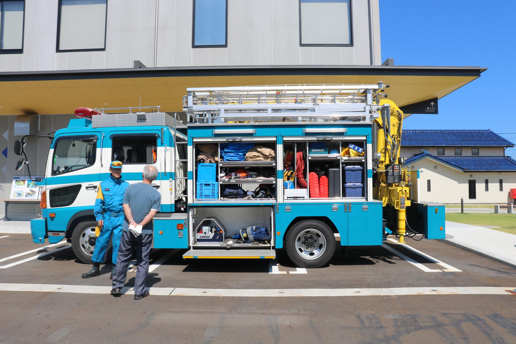 青白のカラーではしごやクレーンが整備された救助工作車（レスキュー車）が展示されており、扉が開けられいろいろな災害救助用の道具が収納されている救助工作車（レスキュー車）の写真