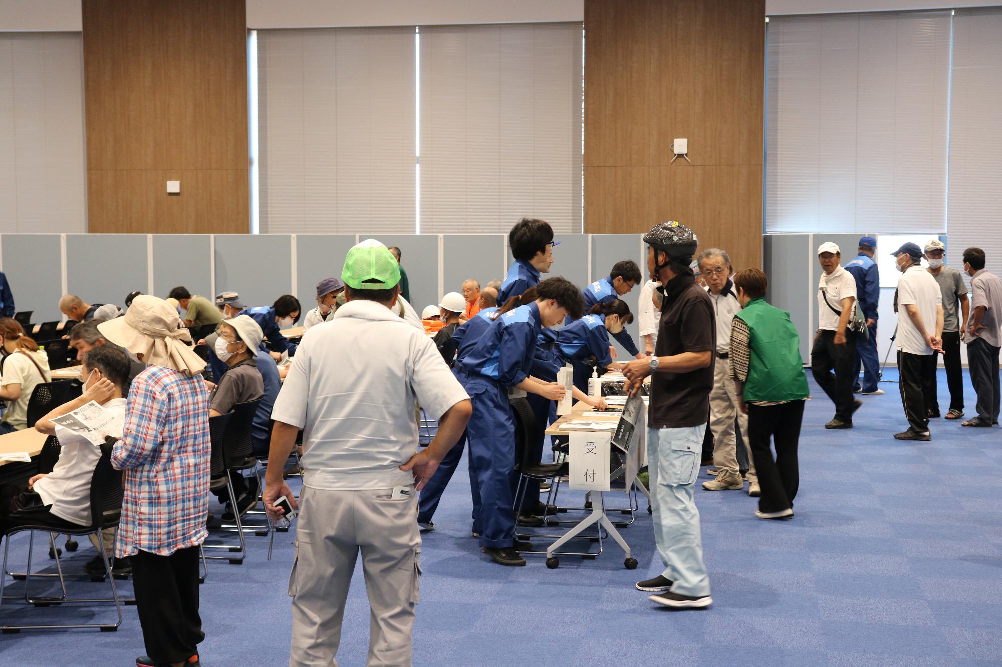 活動服を着た職員の方々が受付で市民の方々の対応を行っている訓練の様子の写真