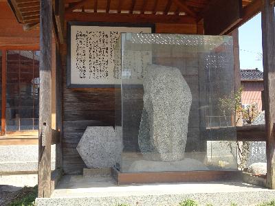 屋根付きの木造の建物に収められ、透明なケースに入っている松尾芭蕉の句碑の写真