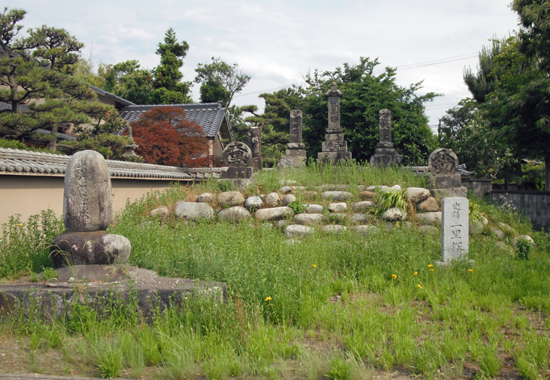 石が積み上げられて円球状の土盛りがされており、頂上に石碑が建っている一里塚（南側）の写真