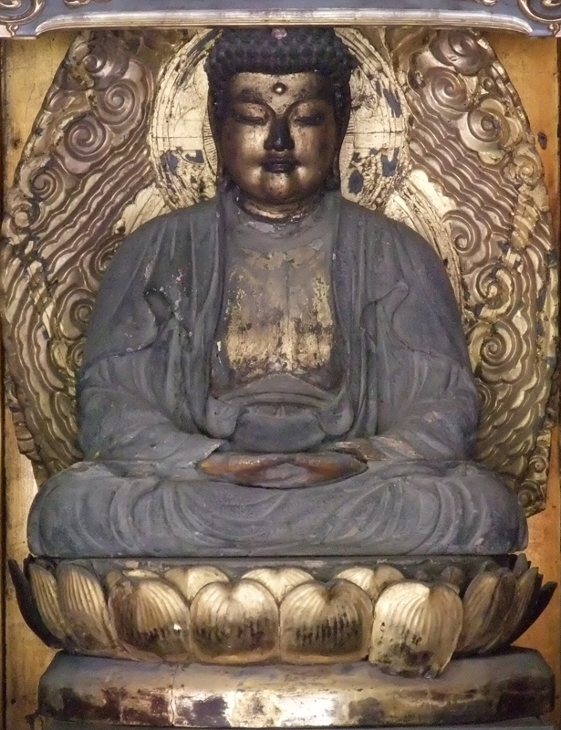 蓮華座の上で 両手の手のひらを上にして腹前で上下に重ね合わせて座っている優しい表情の釈迦如来坐像の写真