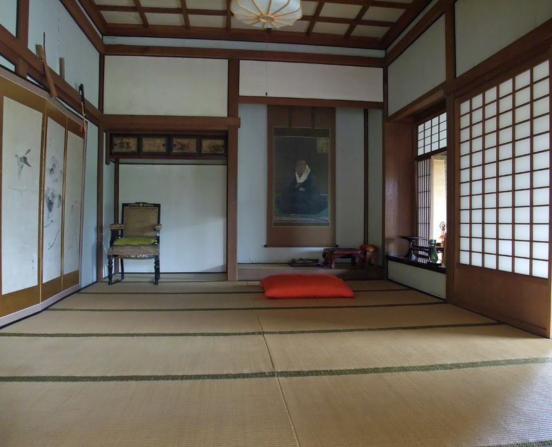 床の間に掛け軸が掛けられ、左側に古い趣のある肘付きの椅子が置かれている畳の敷かれた養照寺上段の間の写真